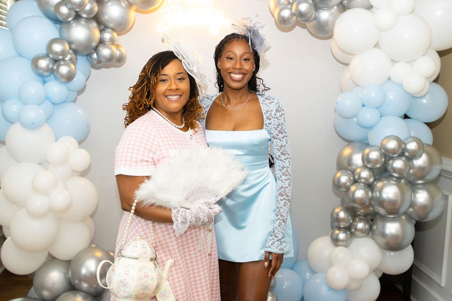 Baby shower celebration setup with blue and silver balloon decorations and white accents.
