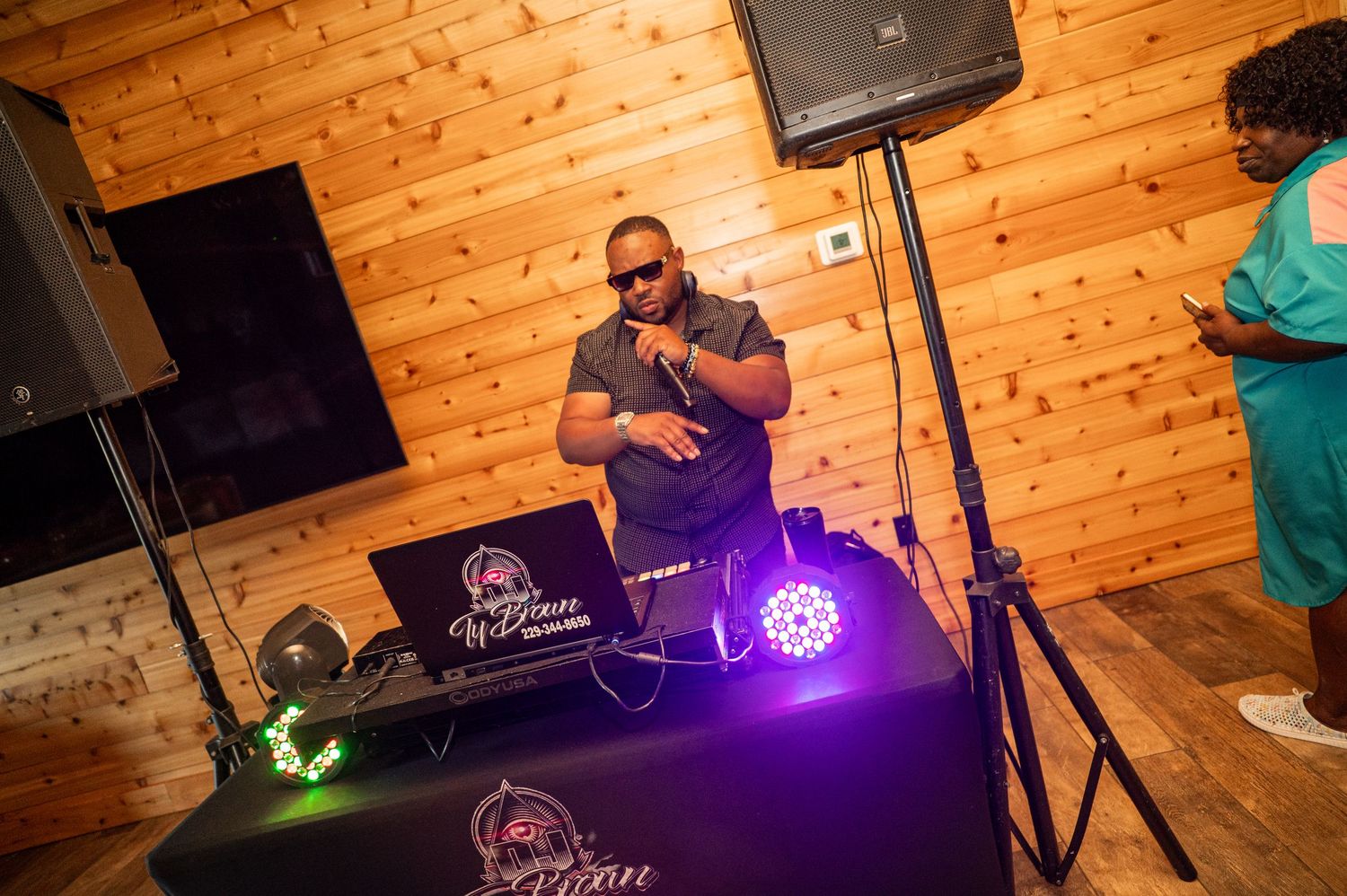 DJ performing at wedding reception with professional equipment and purple stage lighting.