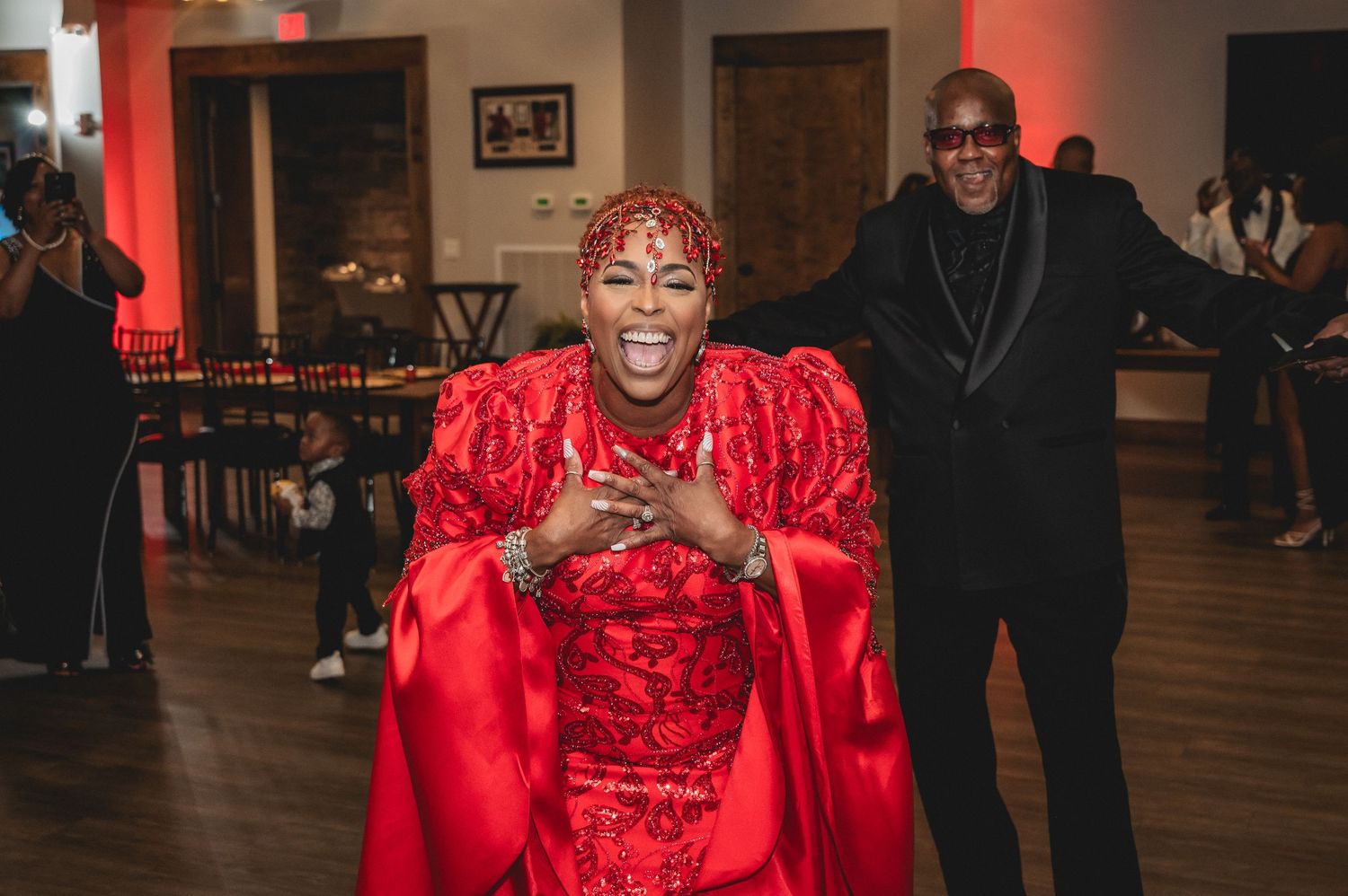 A celebration venue decorated in vibrant red with guests mingling on the dance floor.