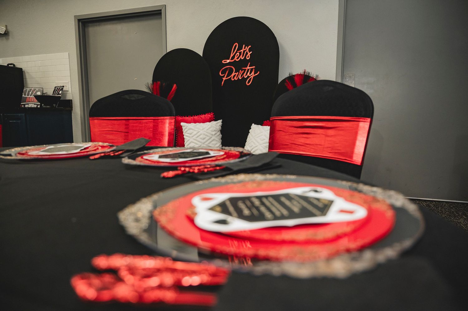 Elegant casino-themed party setup with black and red decor on round tables.