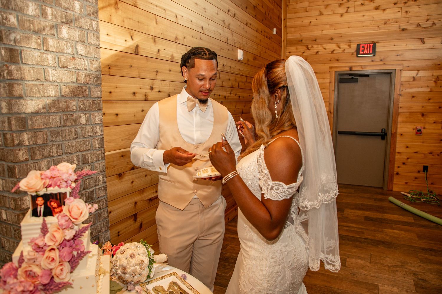 Bride and groom sharing cake cutting moment at wedding reception table.