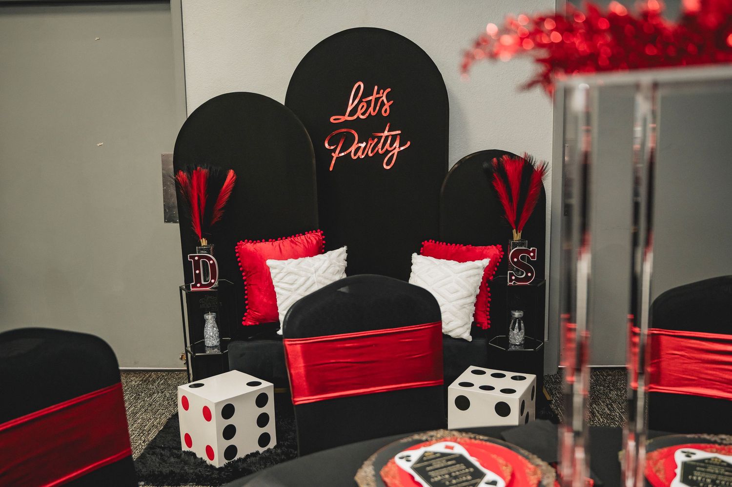 A casino-themed party setup with black chairs, red cushions, and decorative dice against a dark background.