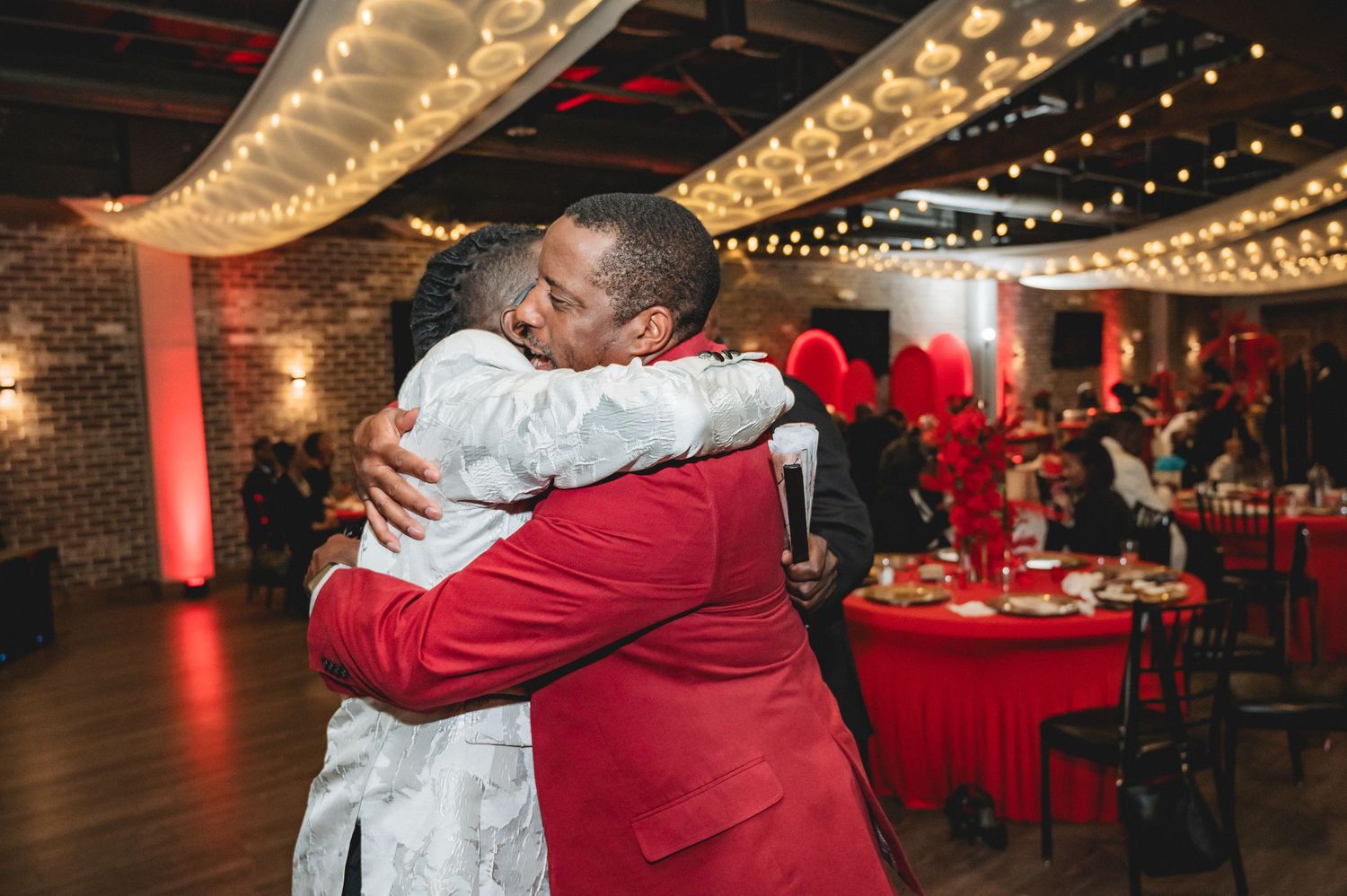 Guests dancing and celebrating under decorative string lights at an indoor party venue.