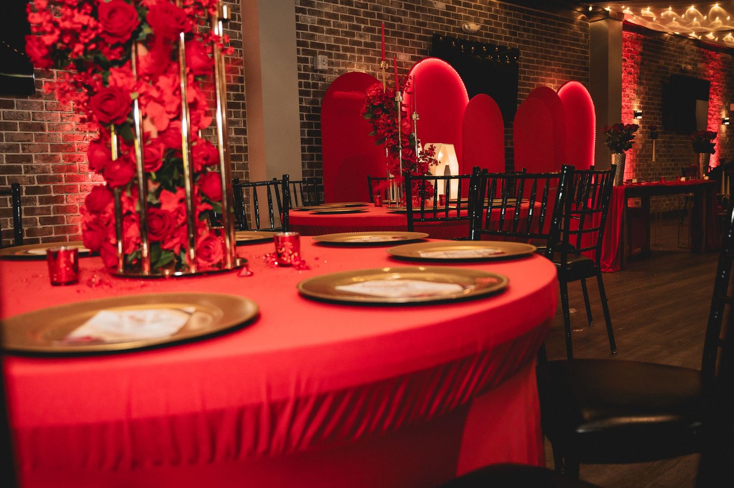 Red tablecloths and festive decorations create an elegant party atmosphere in a brick-walled venue.