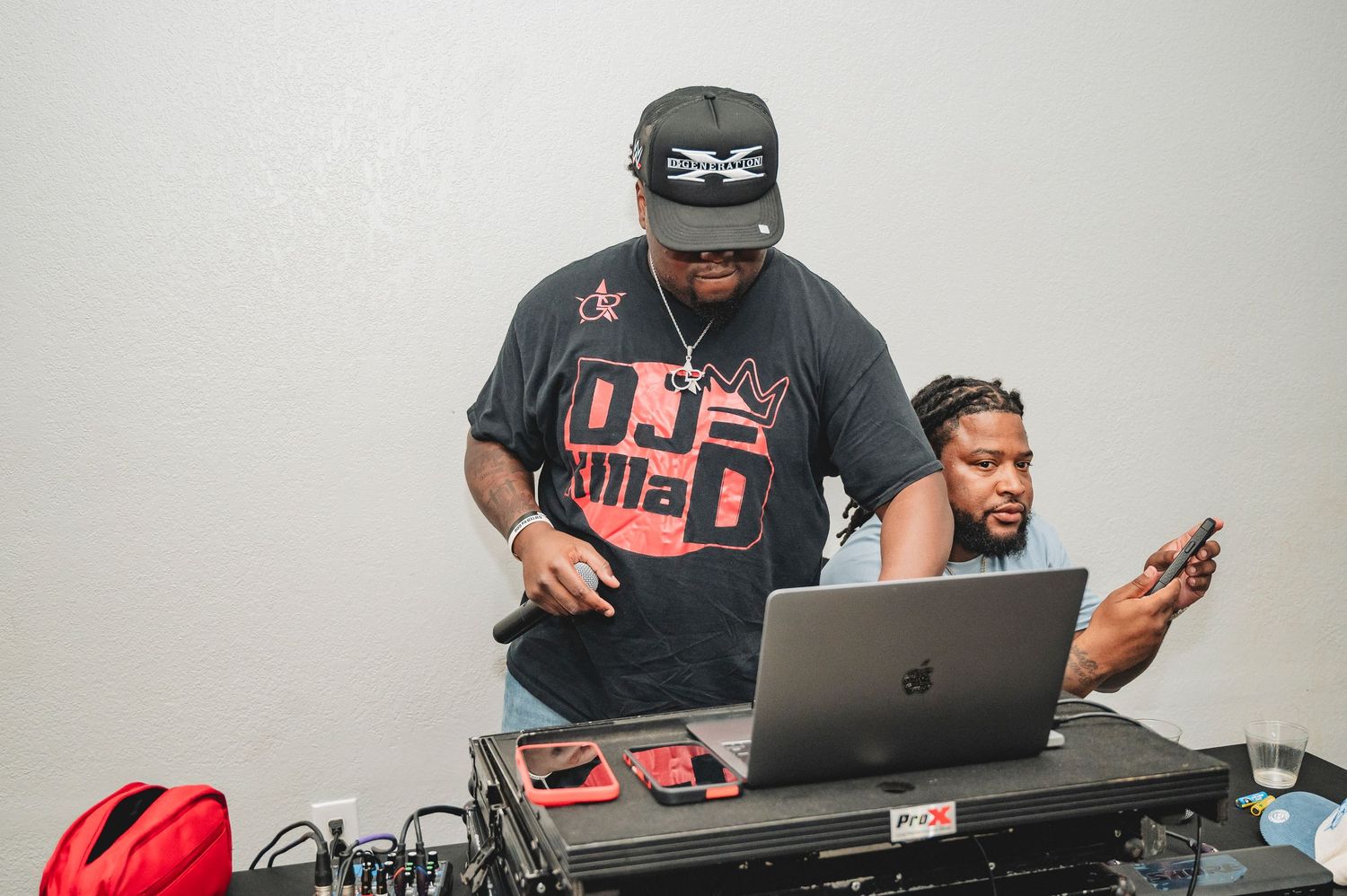 DJ equipment and laptop setup at an event with black and red color scheme.