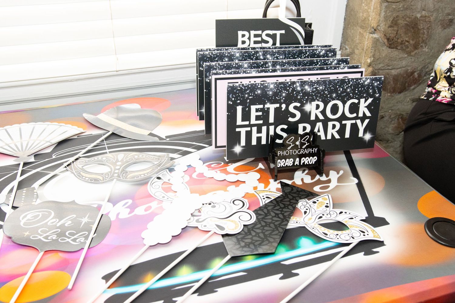 'Let's Rock This Party' sign displayed with retail merchandise and colorful graphic prints on a table.