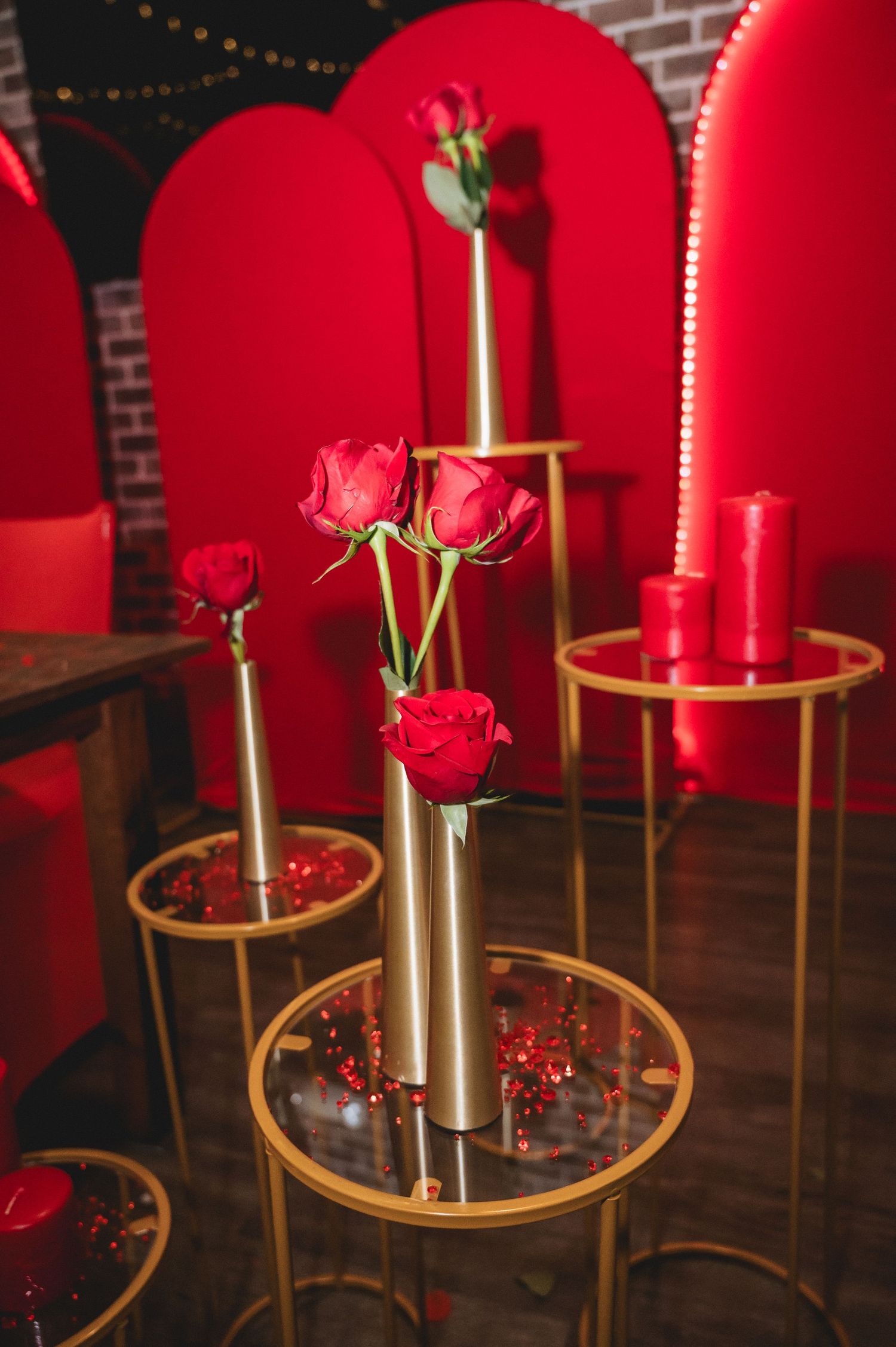 Gold candlesticks with red roses set against plush red velvet chairs create an intimate dining atmosphere.