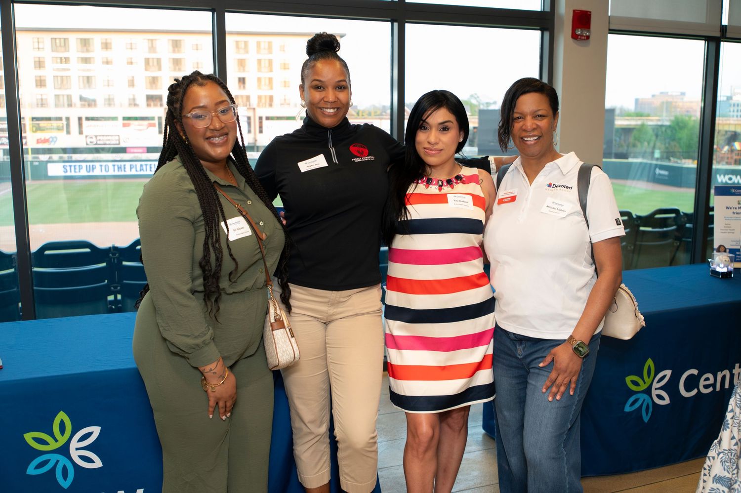 Four women smiling together at a CenterPoint Energy corporate event, posing for a group photo indoors.