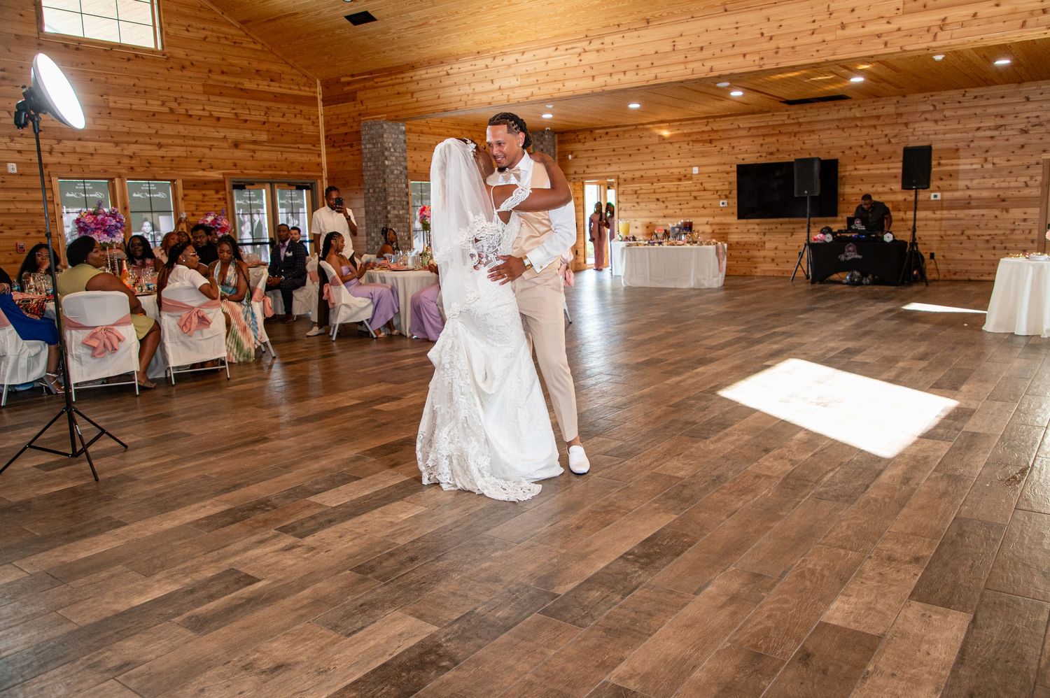 Bride and groom share first dance in spacious rustic wooden wedding reception hall.