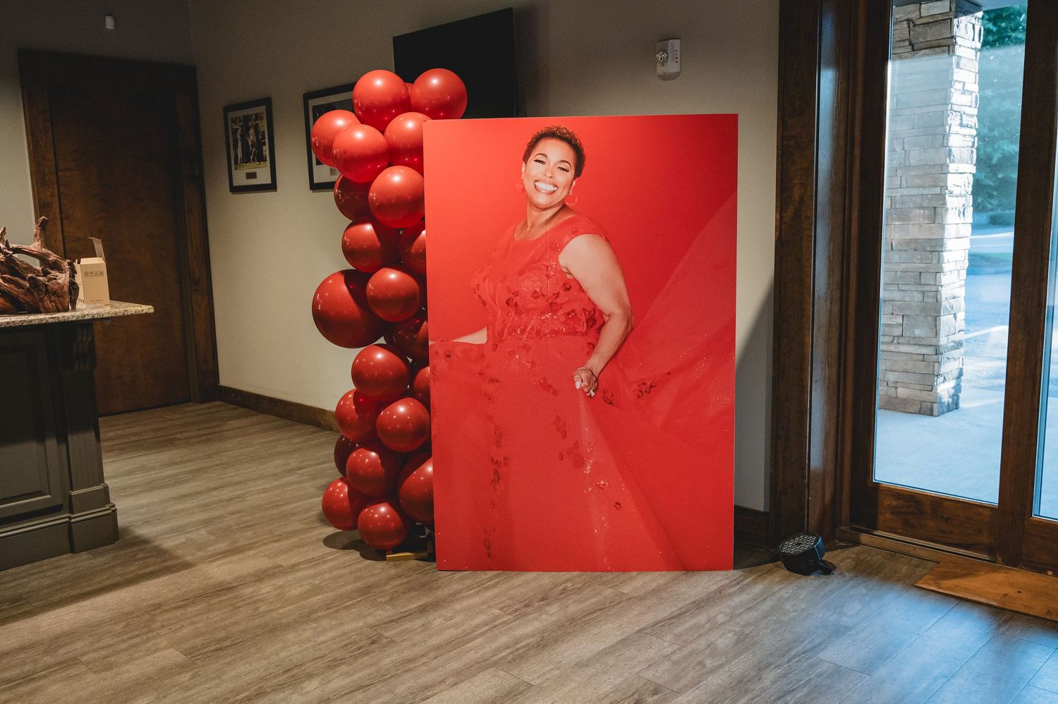 Red balloon arch and backdrop create a dramatic event space setting with white lighting.