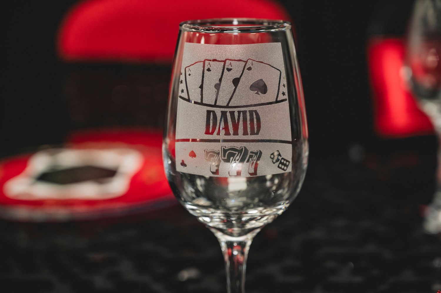 Elegant wine glasses with personalized name tags arranged on a dark table with red accents.
