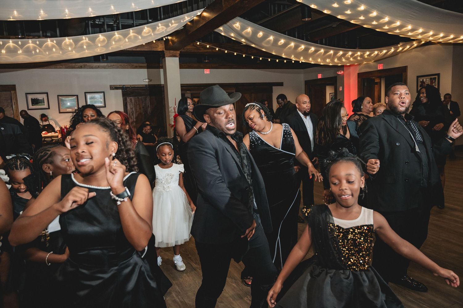 Dance floor scene with string lights overhead and guests enjoying a lively celebration.