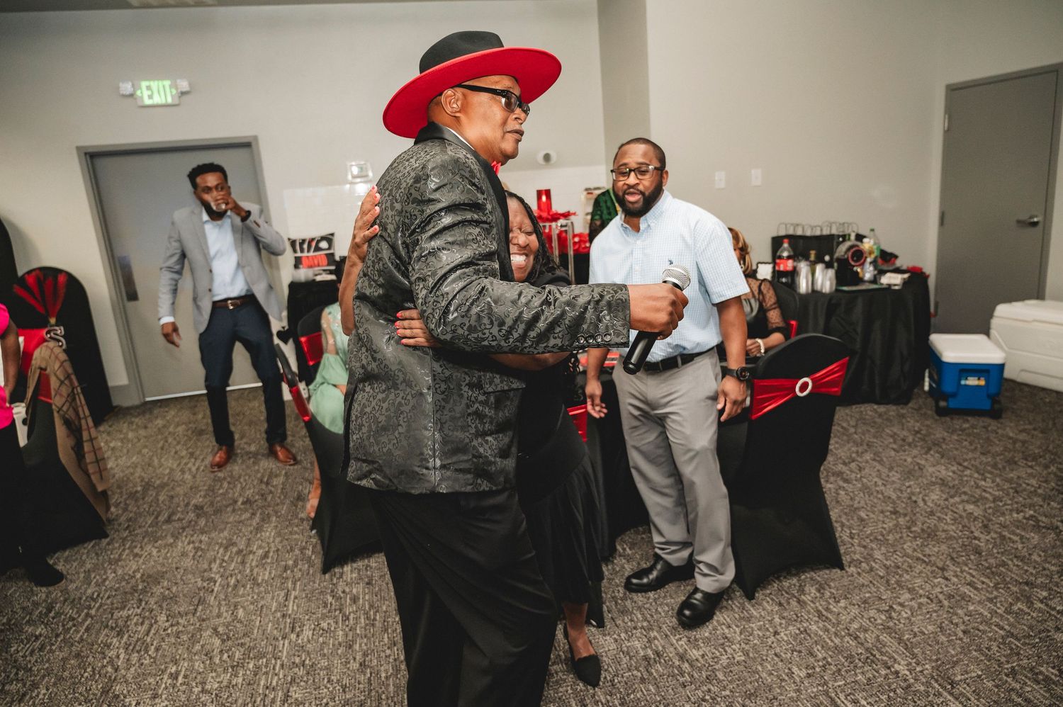 Indoor party venue decorated in red and black theme with guests mingling.