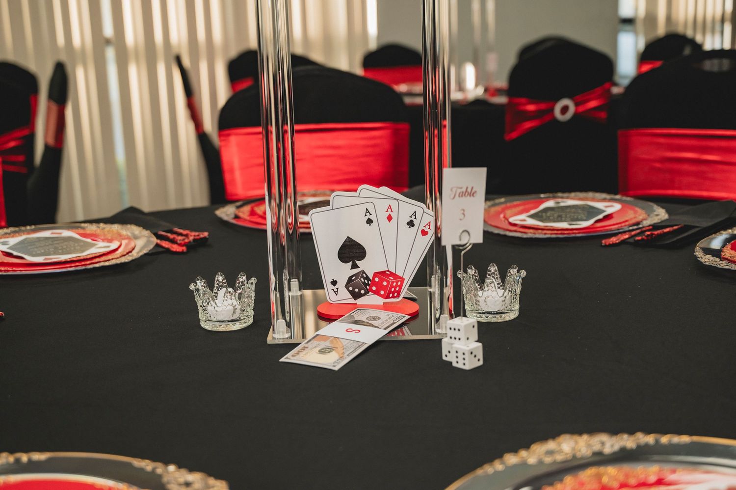 Black tablecloth with playing cards and red accents set for a casino-themed party.