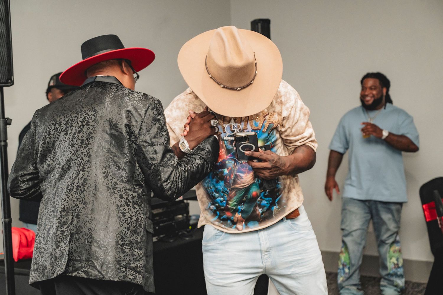 People gathered in a studio space wearing casual clothing with someone in a wide-brimmed hat.