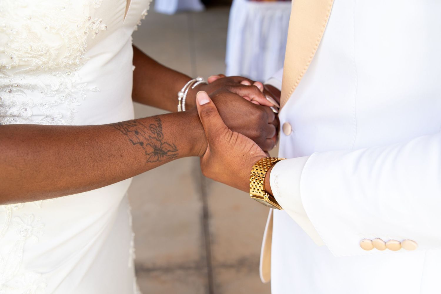 Close-up of bride and groom holding hands during their wedding ceremony.