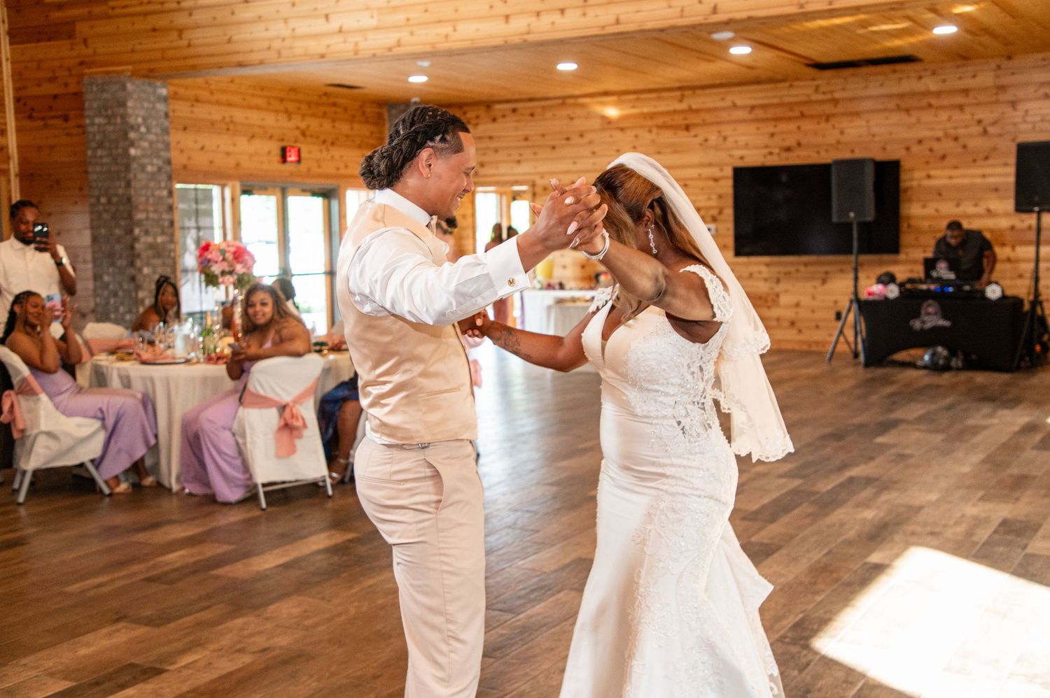 Bride and groom share elegant first dance in rustic wood-paneled wedding reception venue.