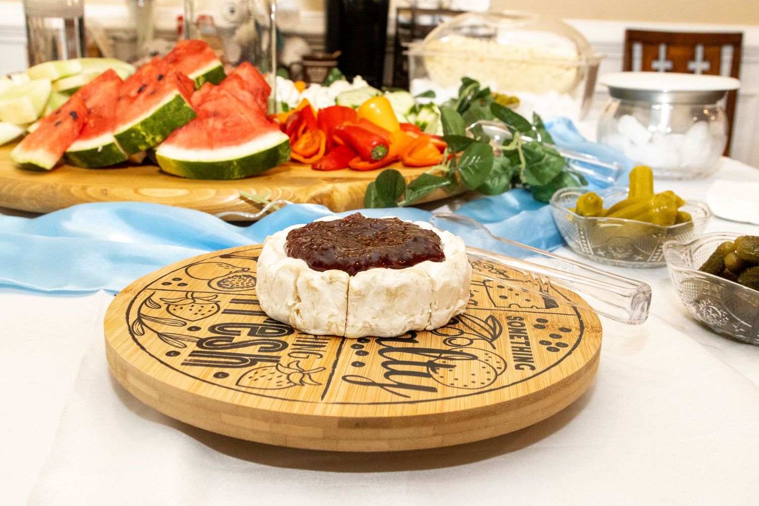 A charcuterie board with various meats, cheeses, fruits and other appetizers arranged on a wooden serving platter.