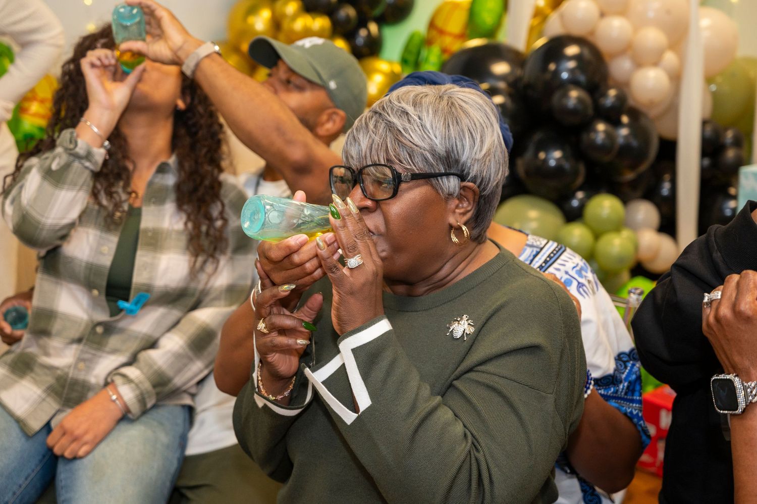 People drinking and celebrating at a lively party with festive decorations in the background.