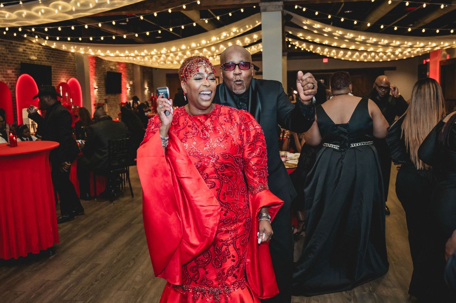 Indoor celebration venue with string lights and red decor creating a festive atmosphere.