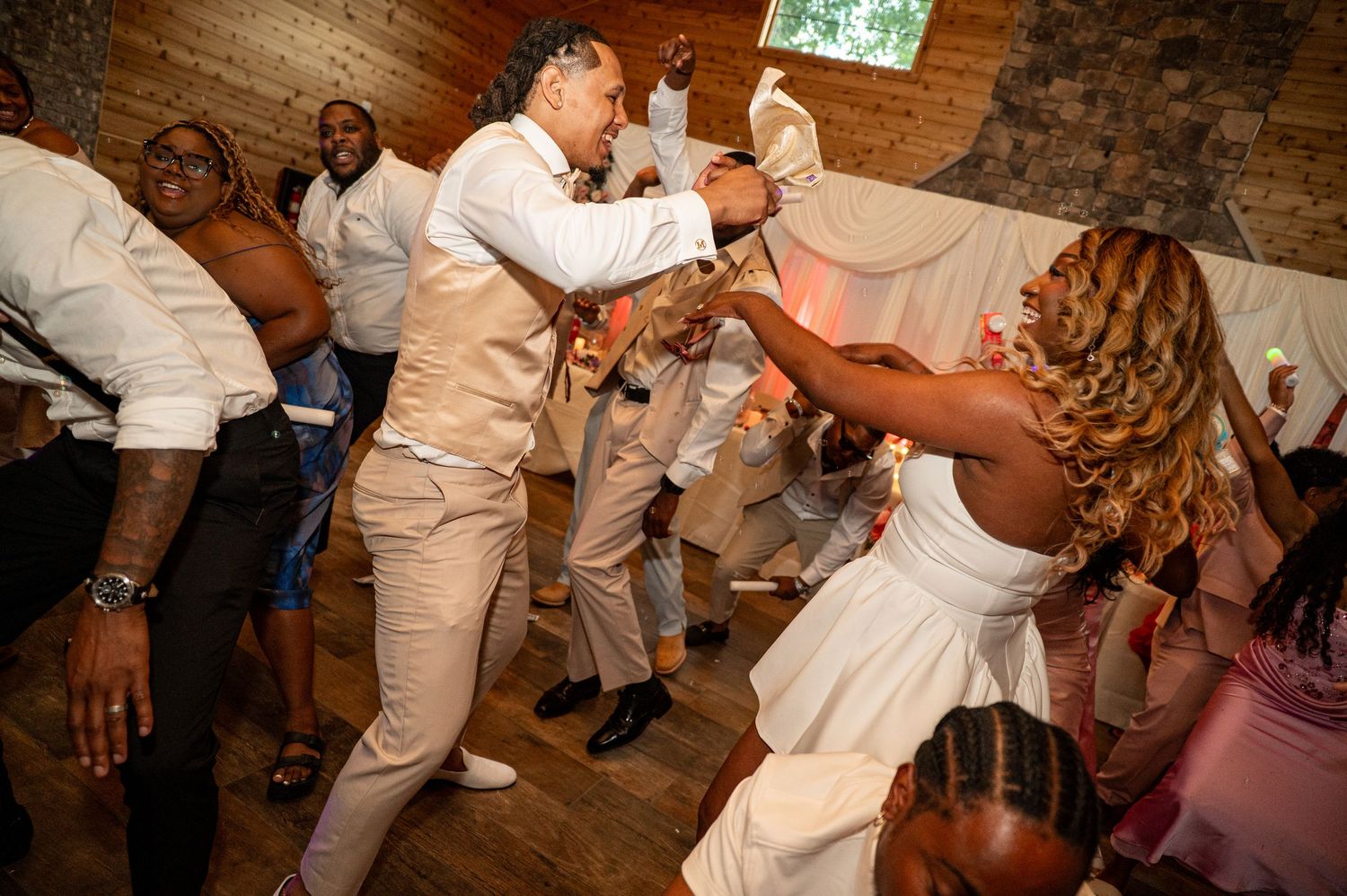 Bride and groom dancing joyfully with guests at their lively wedding reception celebration.