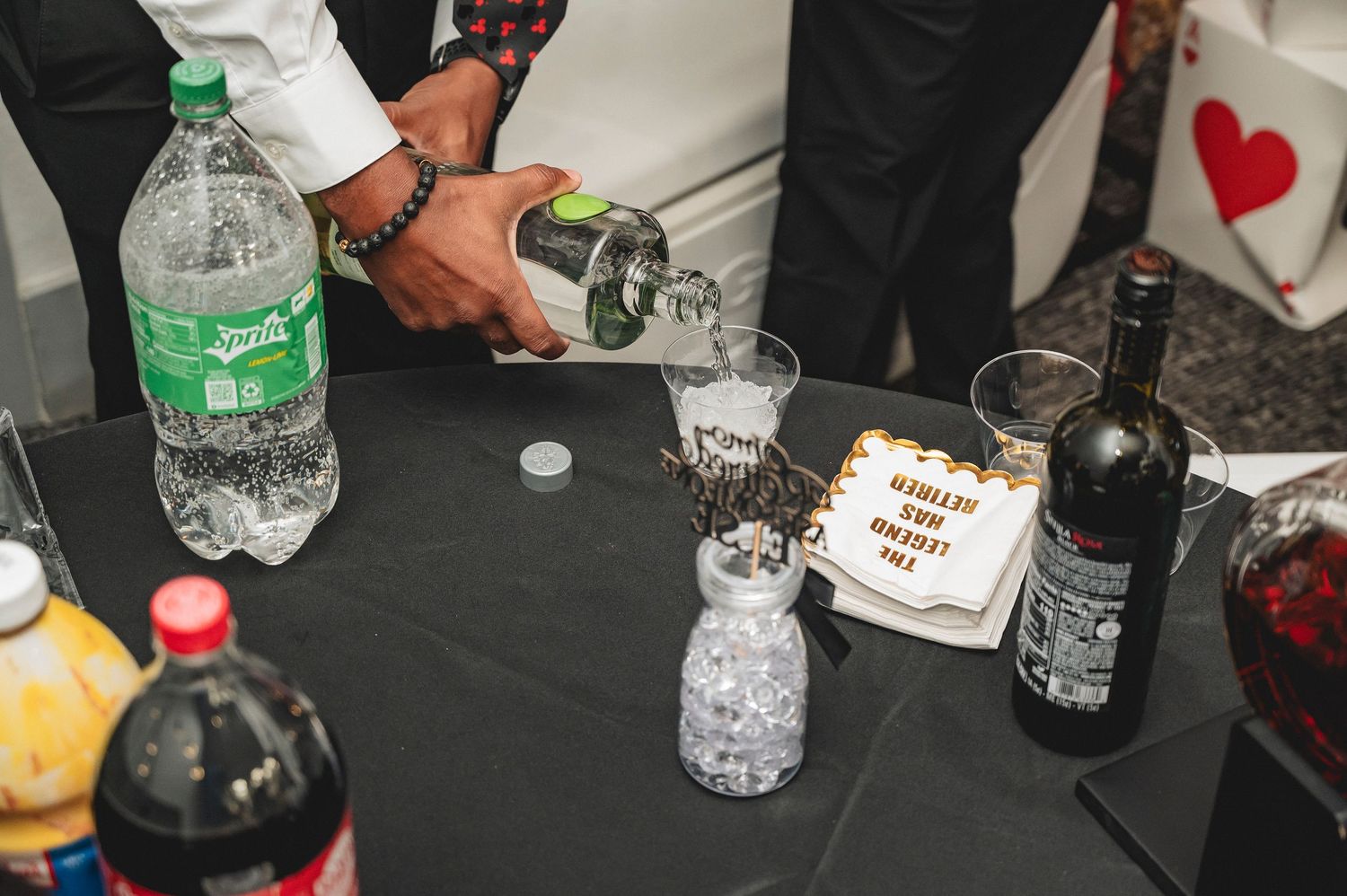 Assorted beverages and party supplies arranged on a black tablecloth.