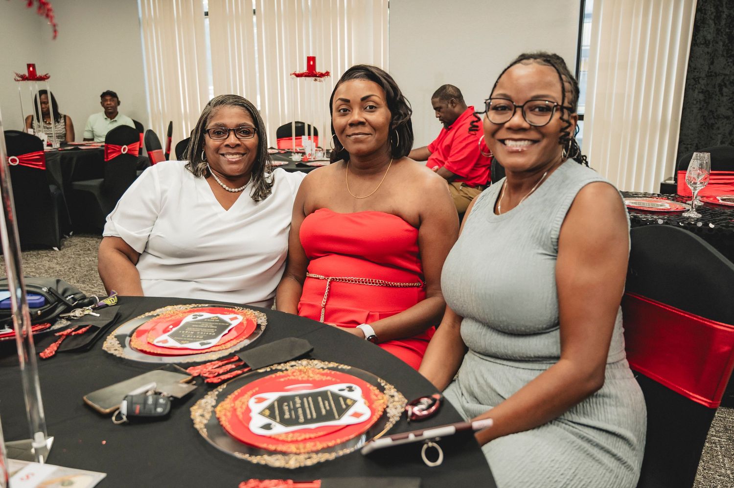 Guests enjoying a festive celebration at tables decorated in red and black casino theme.