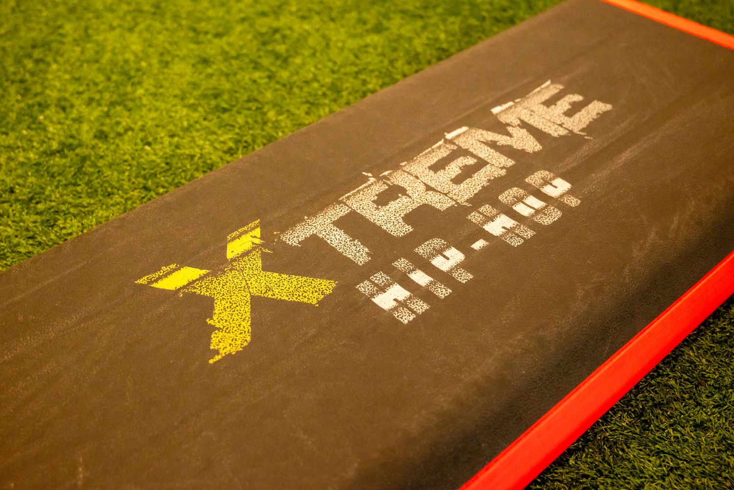 Rustic brown boards with scattered text and symbols lay on lush green grass in close-up perspective.