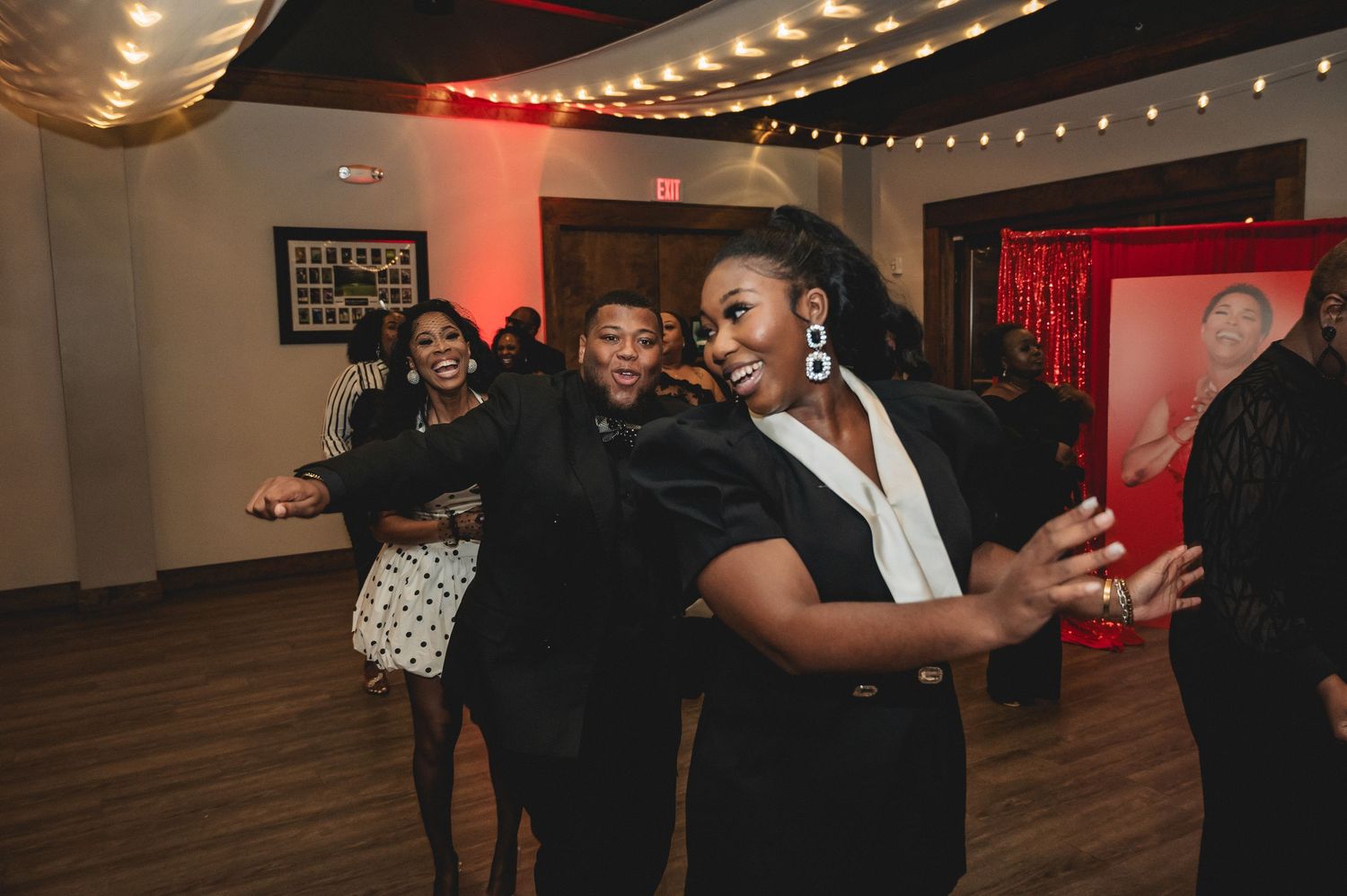 String lights and red decor create ambiance at an indoor celebration venue.