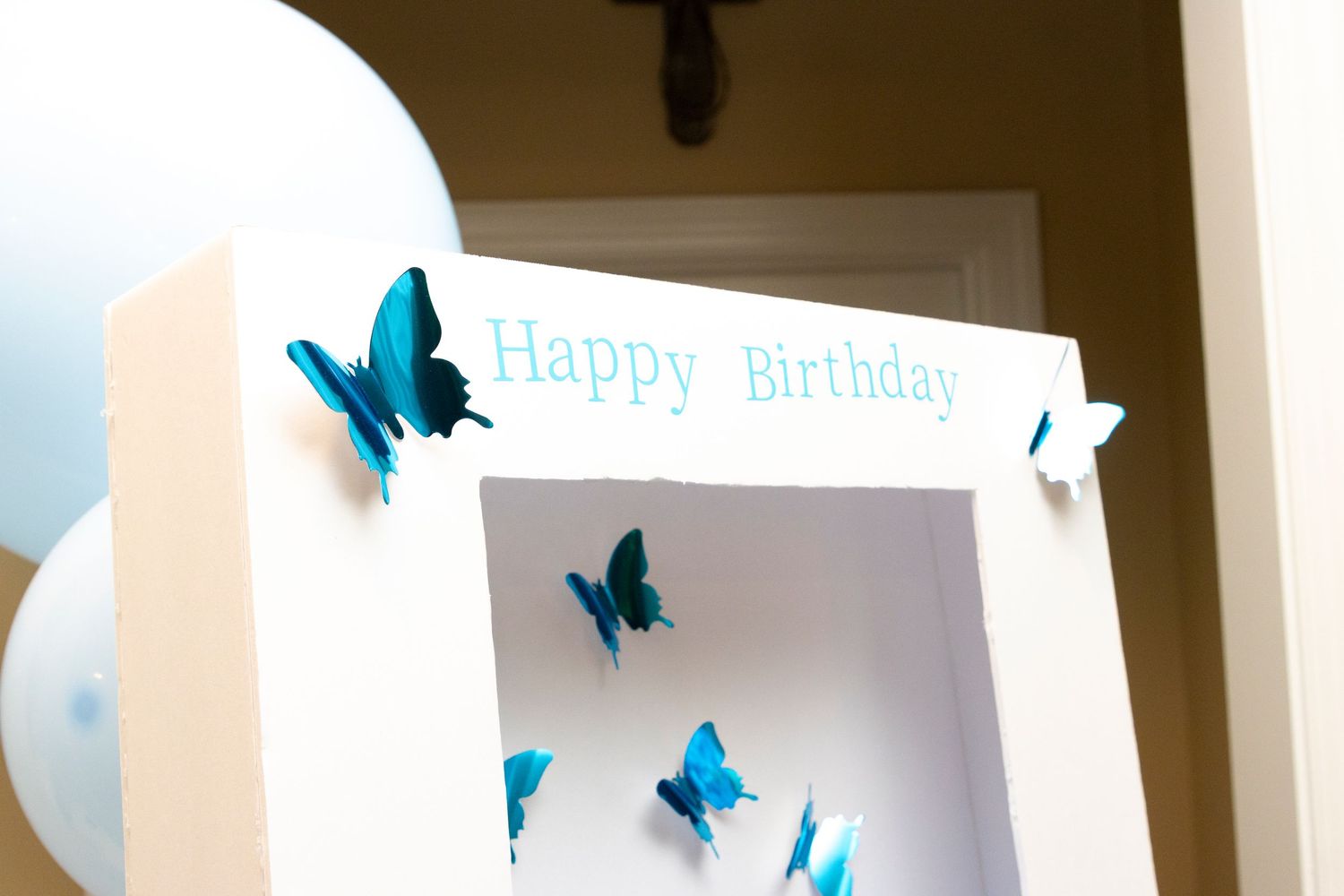 Blue butterflies decorate a white wall with a happy birthday message and party decorations.