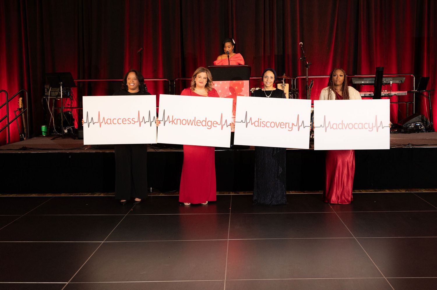 Red stage curtains and lighting create a dramatic atmosphere for a theatrical performance.