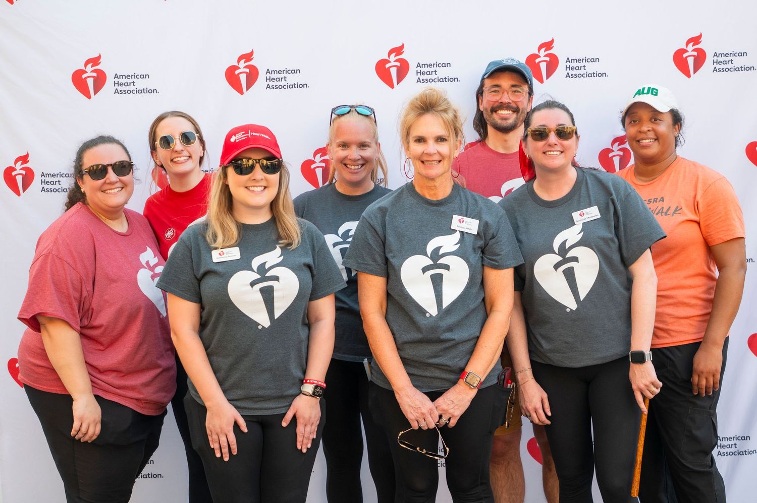 Group of volunteers posing in American Heart Association t-shirts at a charity event backdrop.