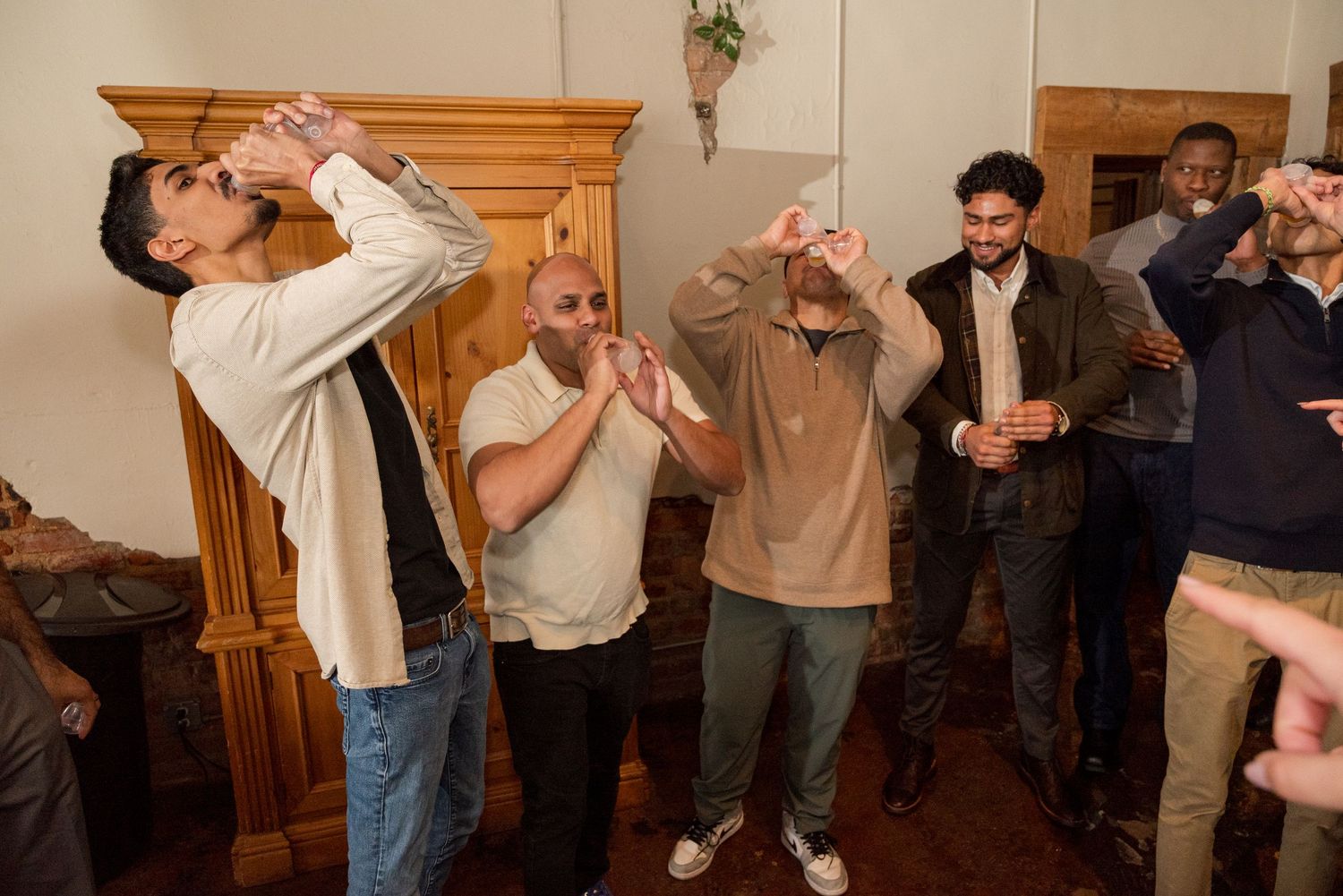 A group of people dancing and celebrating together in a room with wooden paneling and warm lighting.