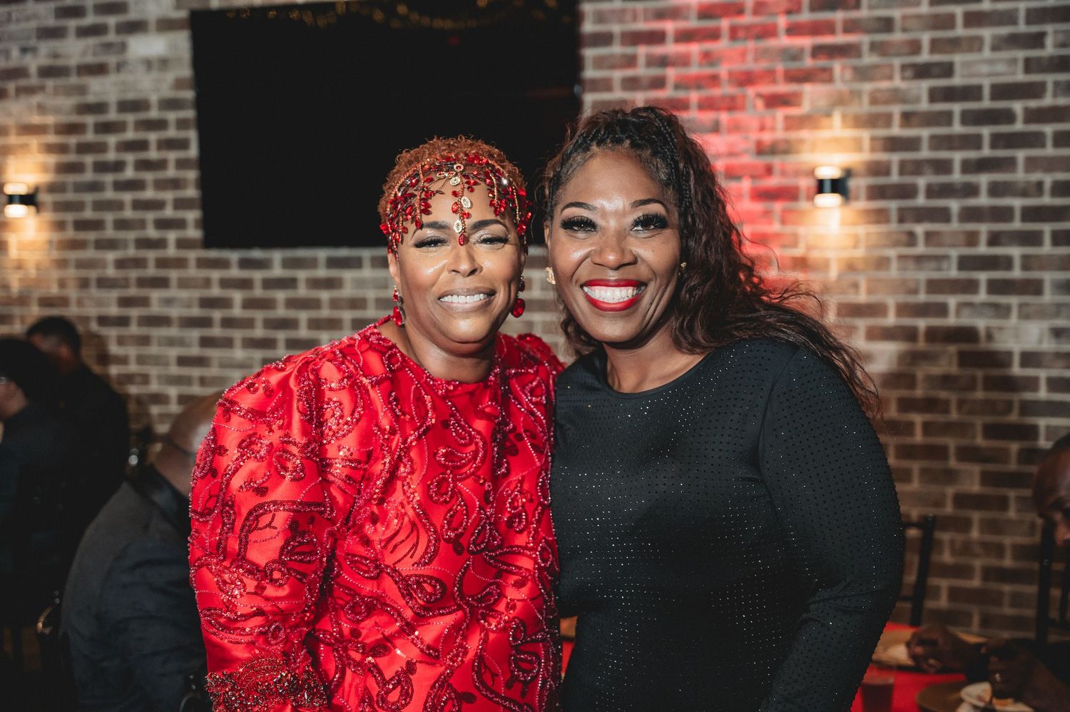 Guests celebrate at an event with red decor and exposed brick walls.