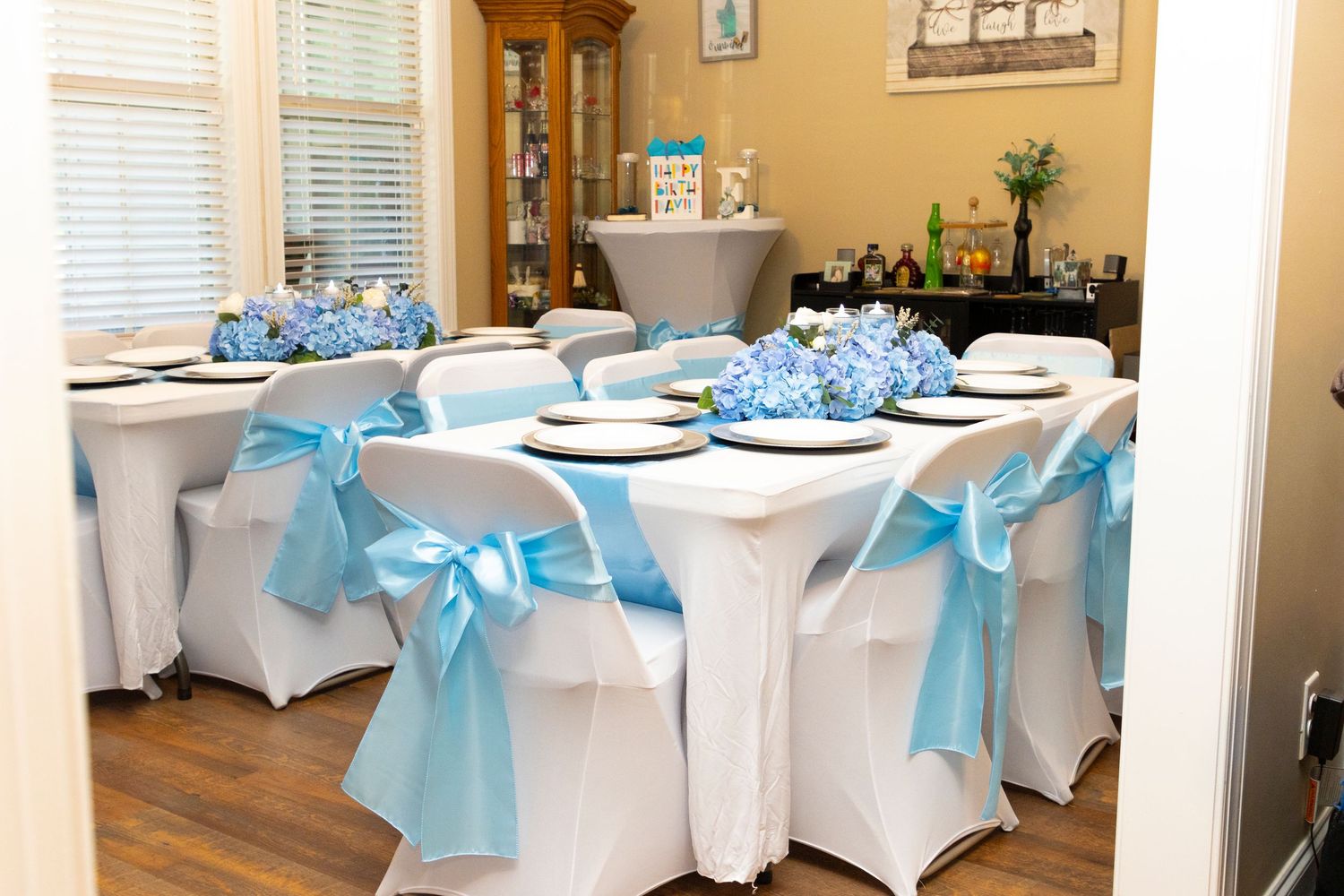 White tablecloths with aqua blue satin bows decorate a banquet room set up for a formal event.