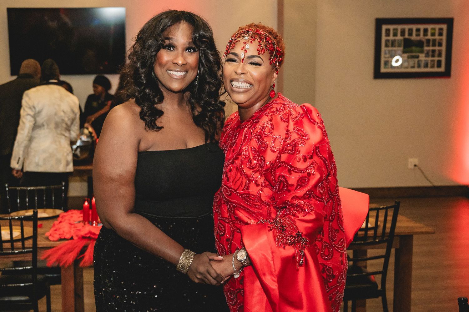 Four glamorous guests pose at an elegant event, with one wearing a striking red ruffled dress and others in black attire.