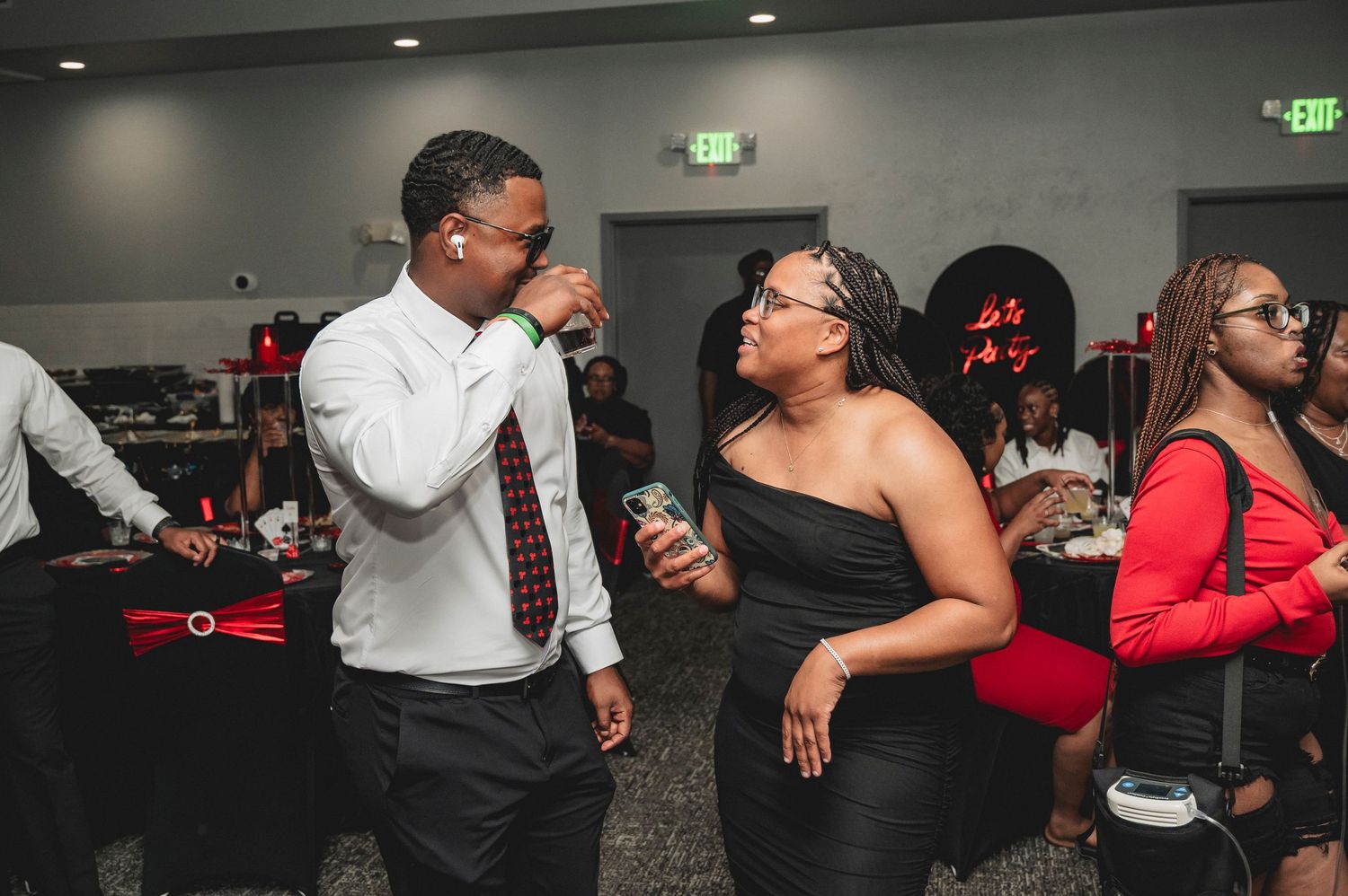 Party guests mingling and dancing in an event space with ambient lighting.