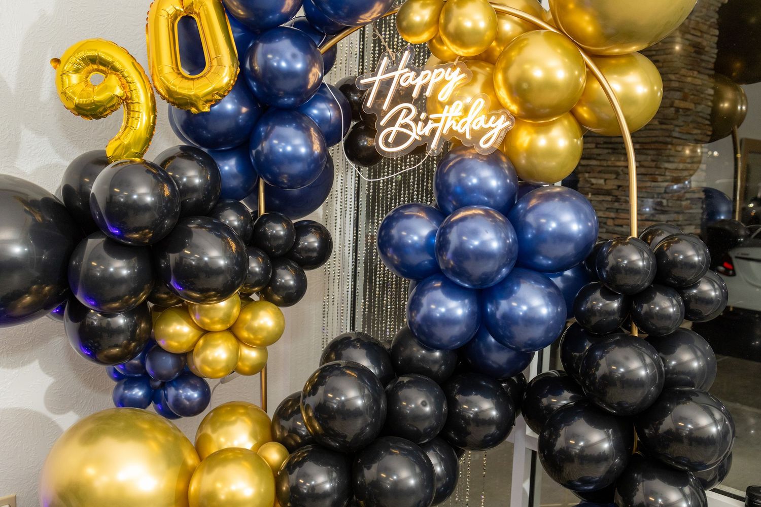Navy blue, gold, and black balloons arranged in an elegant garland style for party decoration.