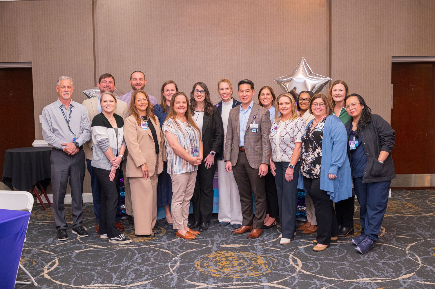 Group of professionals posing together at a corporate awards event in a hotel ballroom with a star balloon.