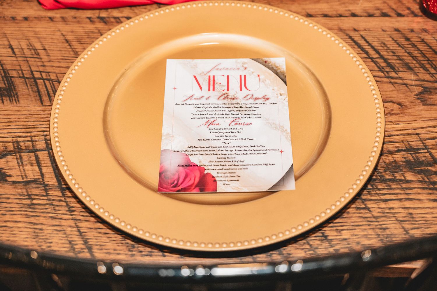 Gold metallic charger plates with menus arranged on a rustic wooden table for an elegant event setting.