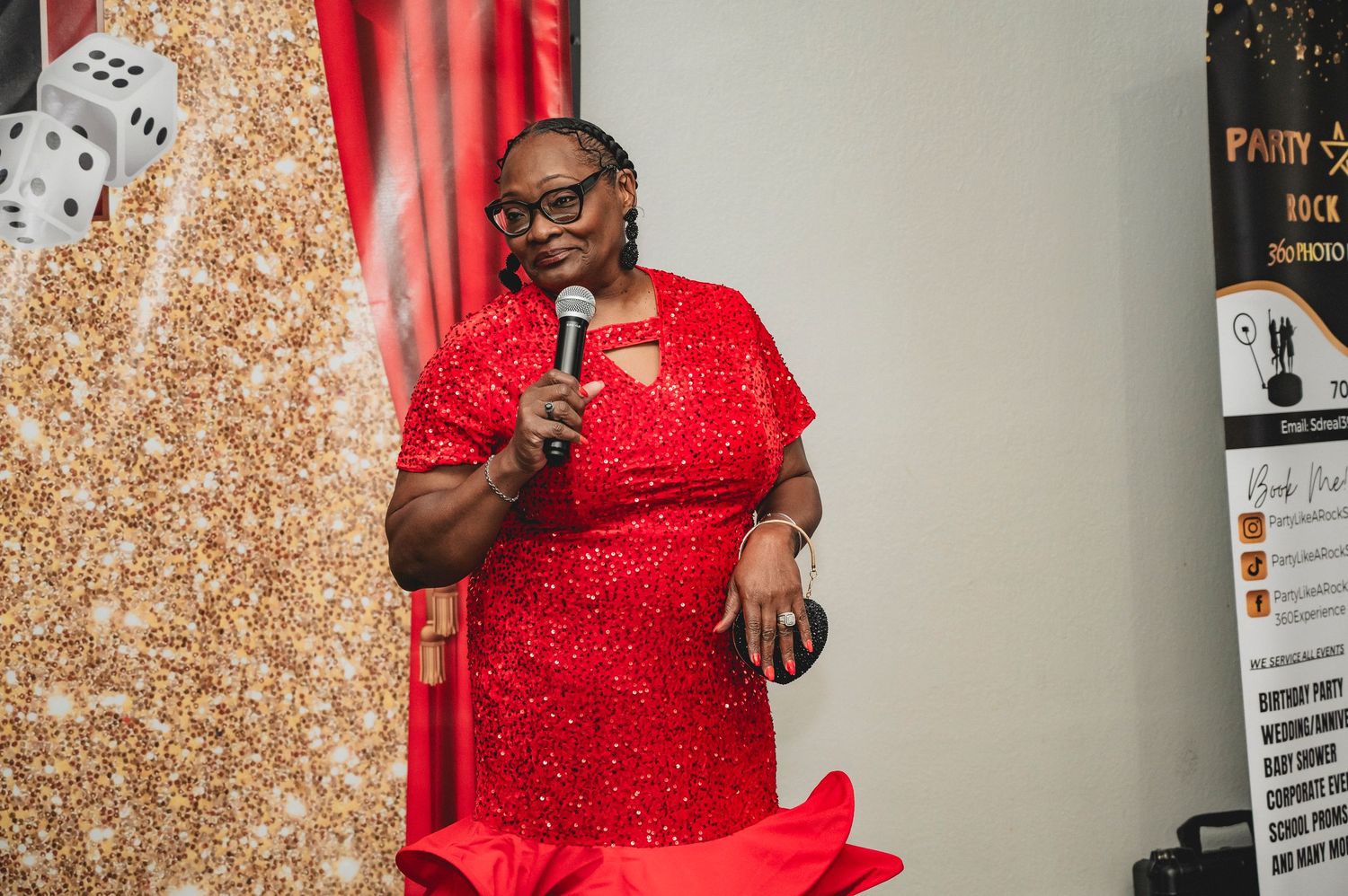 Person in sparkling red dress speaking into microphone at indoor event.