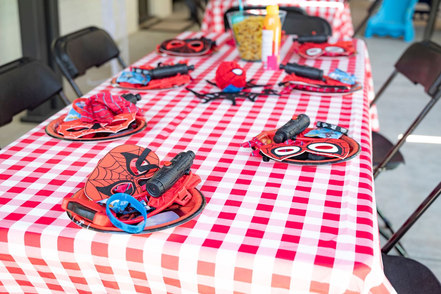 Spider-Man themed birthday party table with red checkered tablecloth, character plates, and decorations set for children.