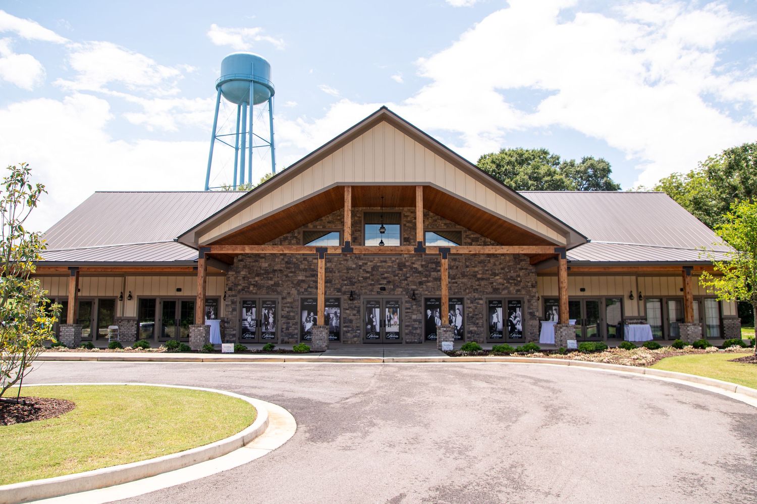 Rustic stone and wood wedding venue exterior with water tower in background.