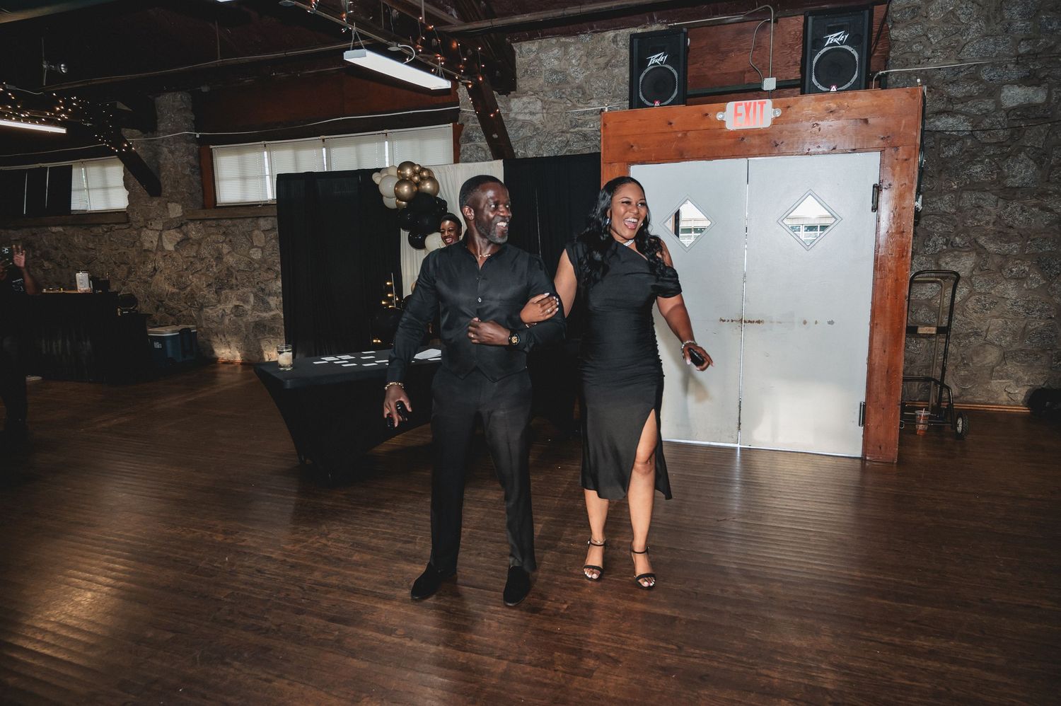 Wedding guests dancing and having fun in a rustic brick venue with wooden floors.