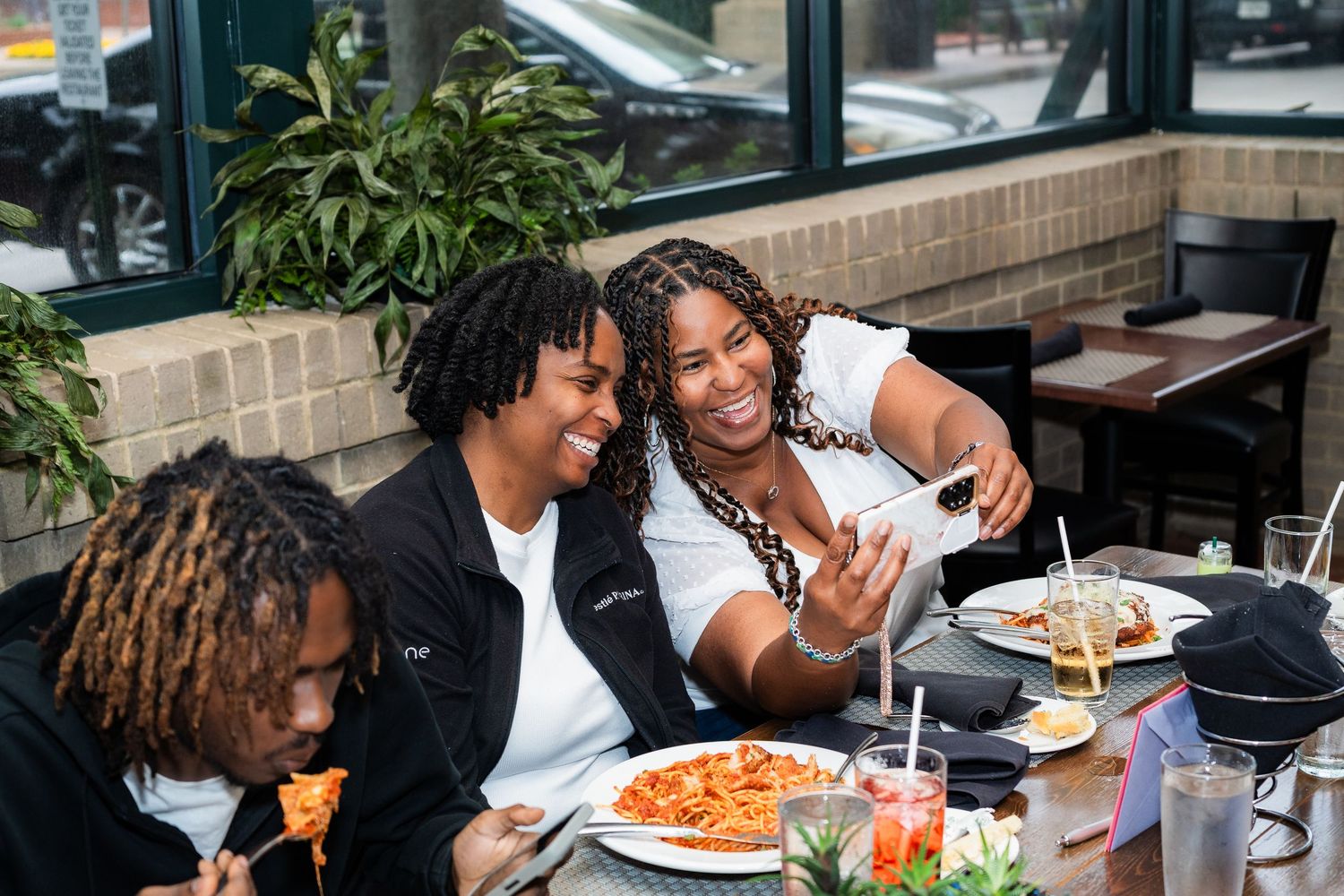 A group enjoying drinks and food on an outdoor restaurant patio during a sunny day.