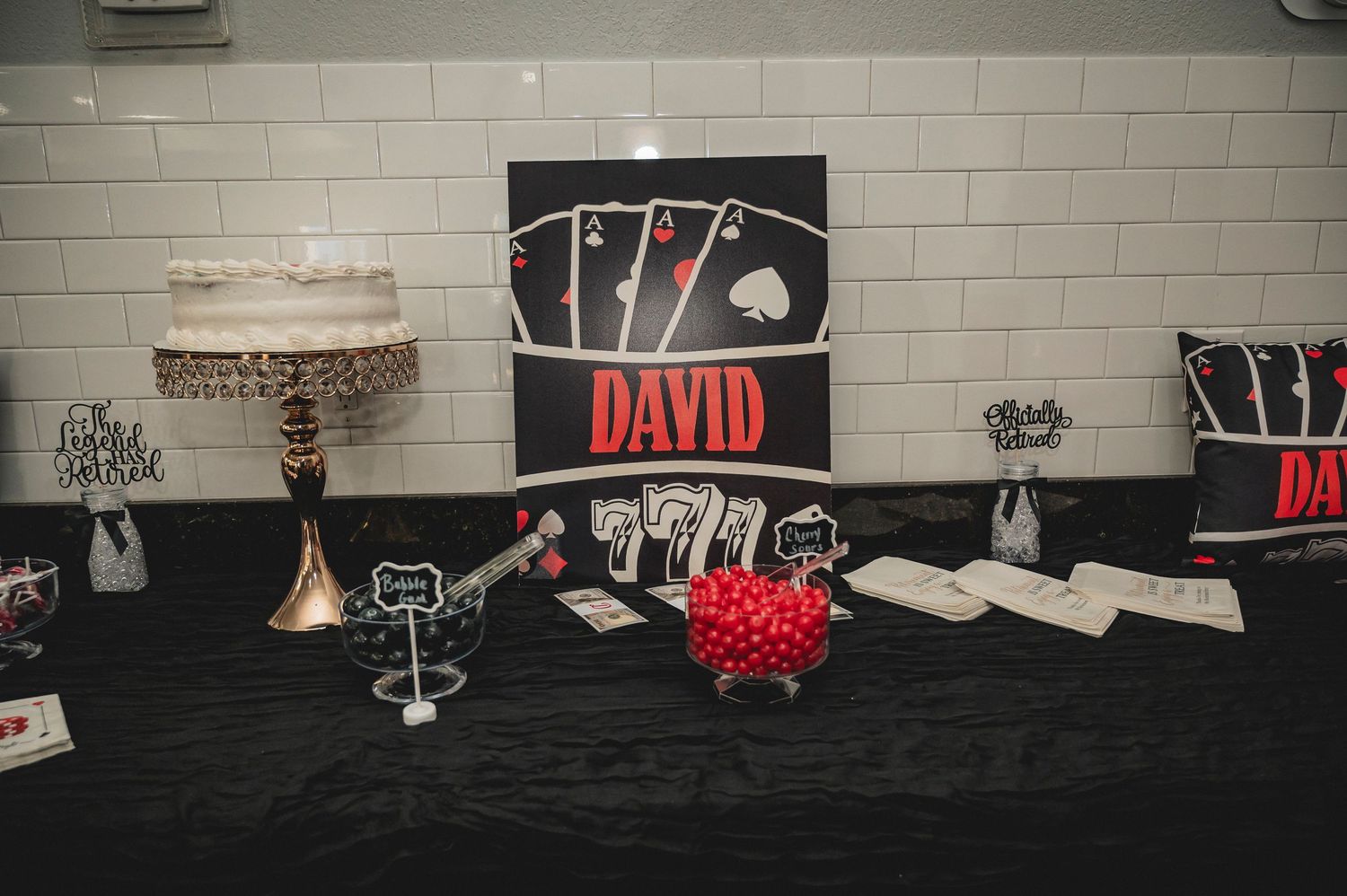 Casino-themed party table setup with black and red decorations featuring playing card motifs and name DAVID.