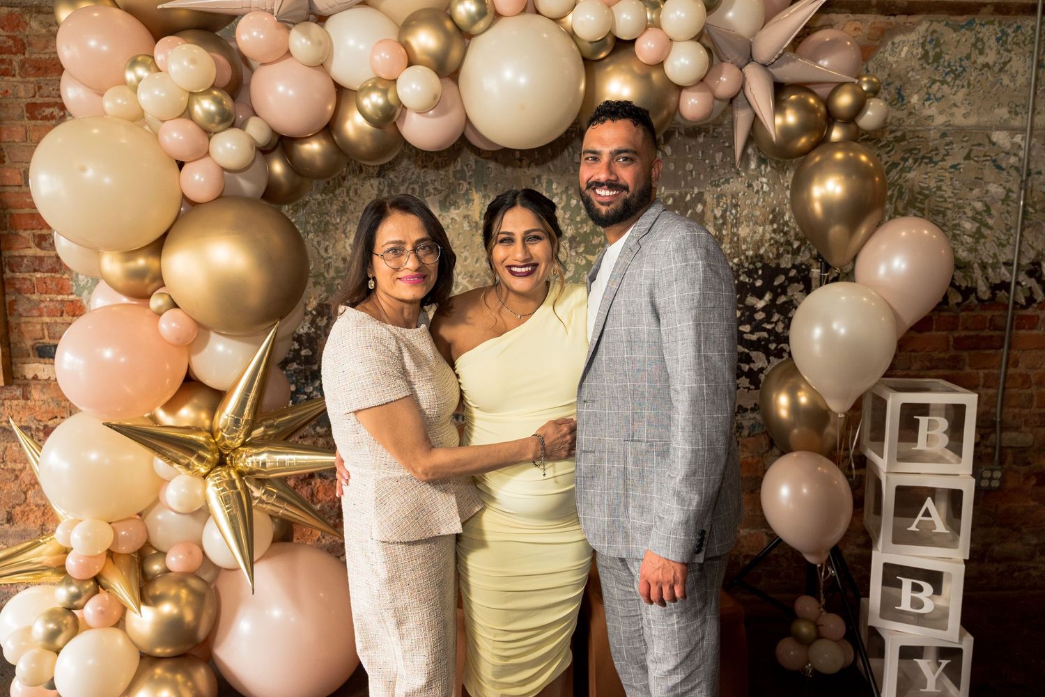 A group photo session with a balloon arch backdrop in blush pink and gold colors for a special celebration.