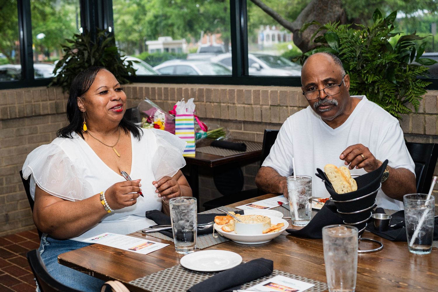 Diners enjoy a casual meal while engaging in lively conversation at an outdoor restaurant table.
