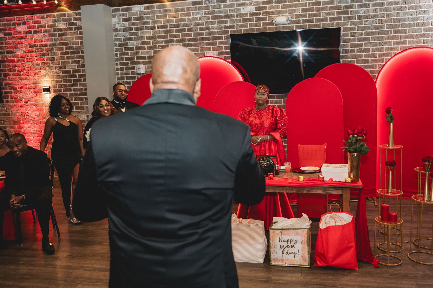 Reception venue featuring exposed brick walls, string lights and elegant red decor elements.