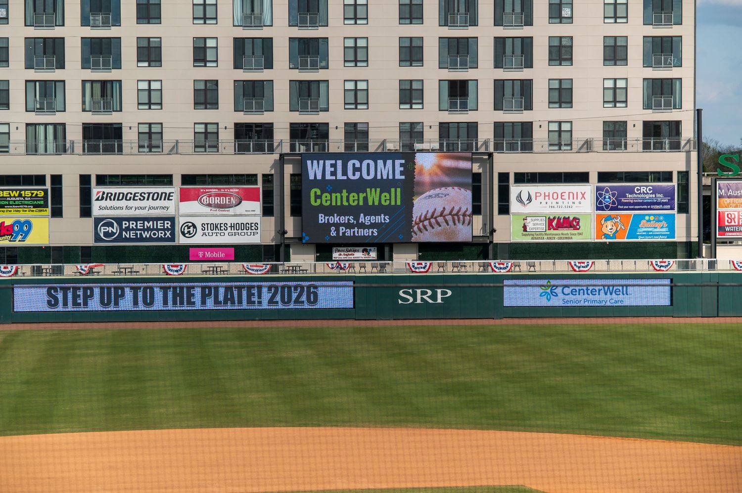 Baseball stadium outfield wall with multiple advertising billboards and signage displayed during a game.